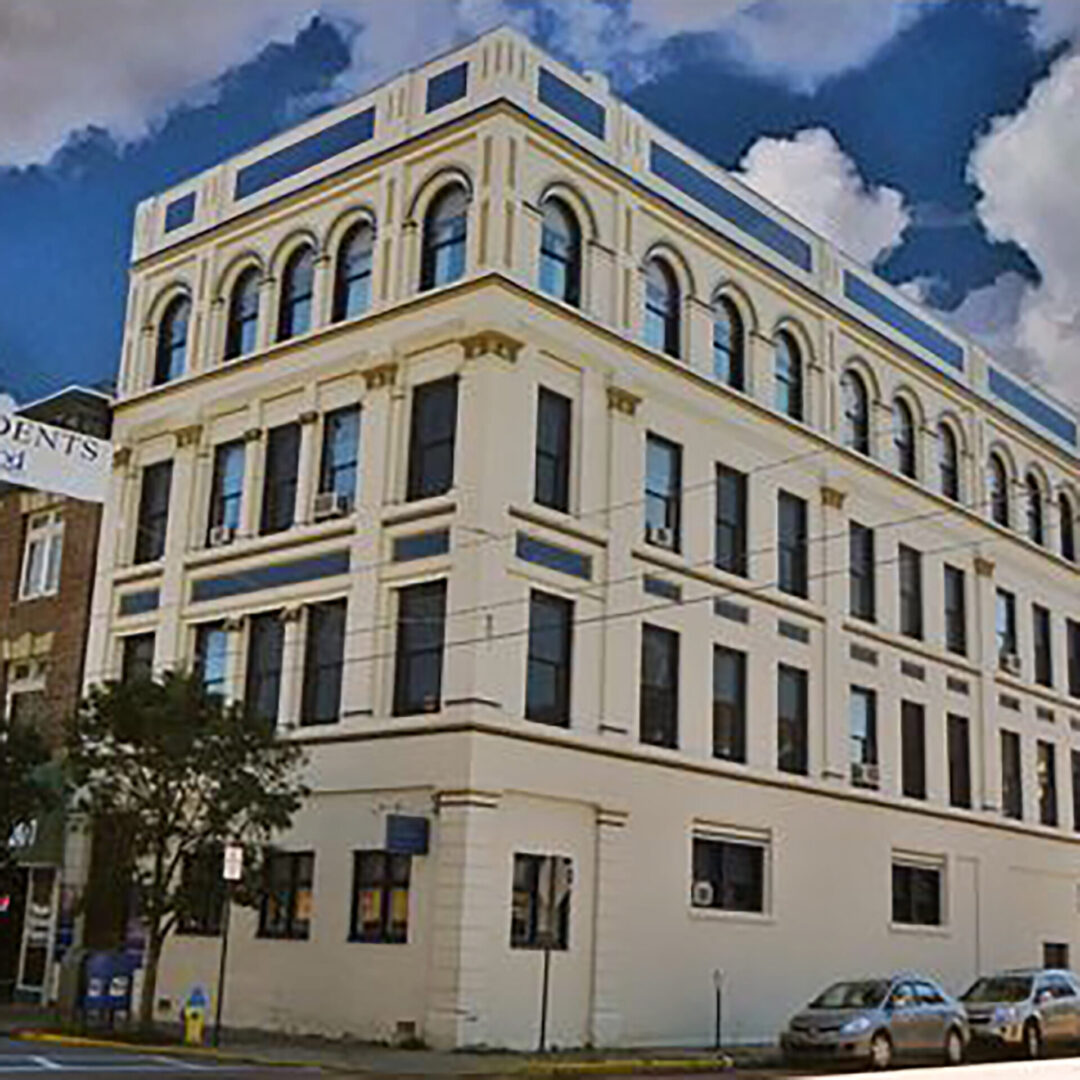 A large building with many windows on the corner of a street.