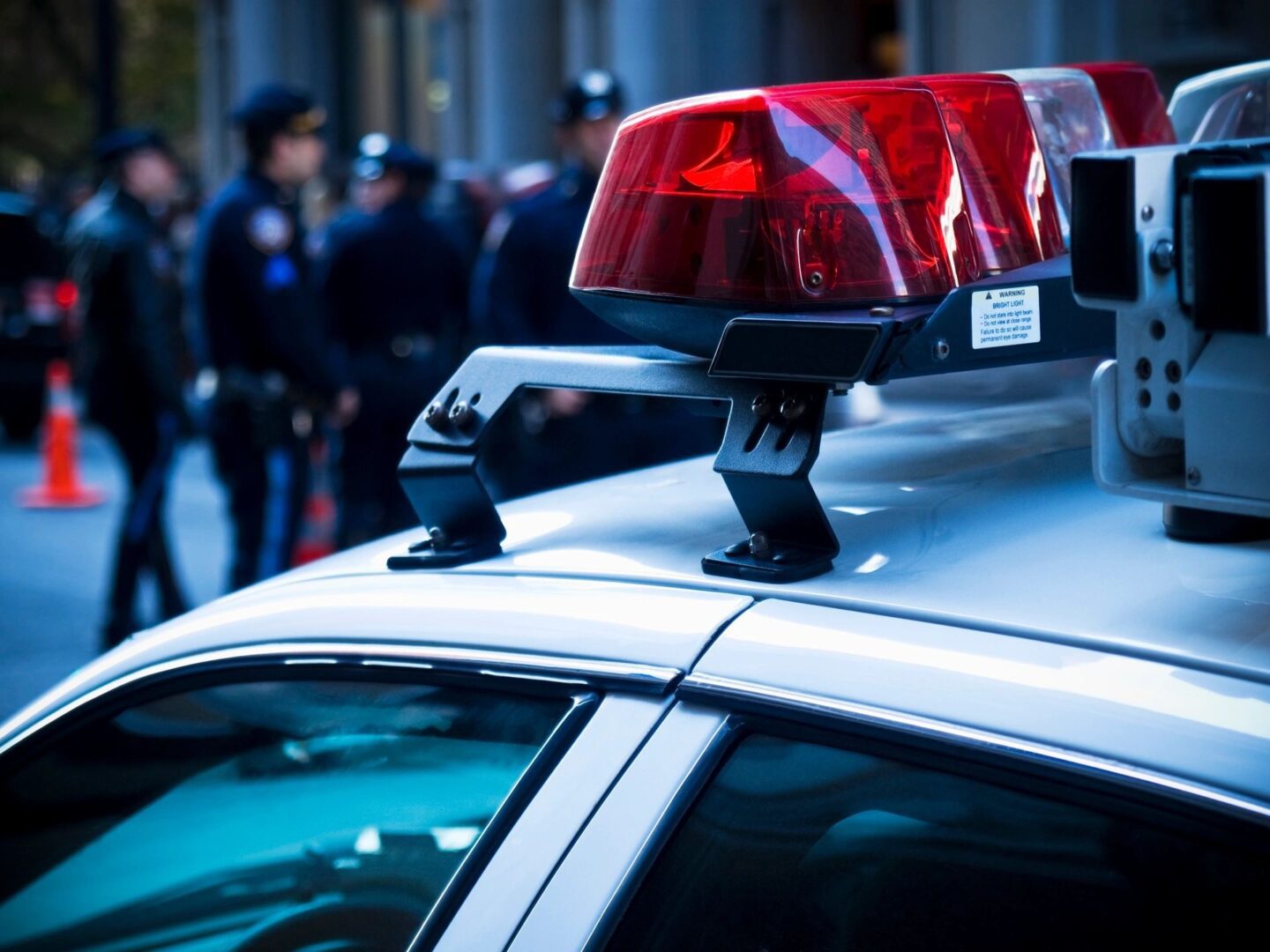 A police car with its lights on and people in the background.